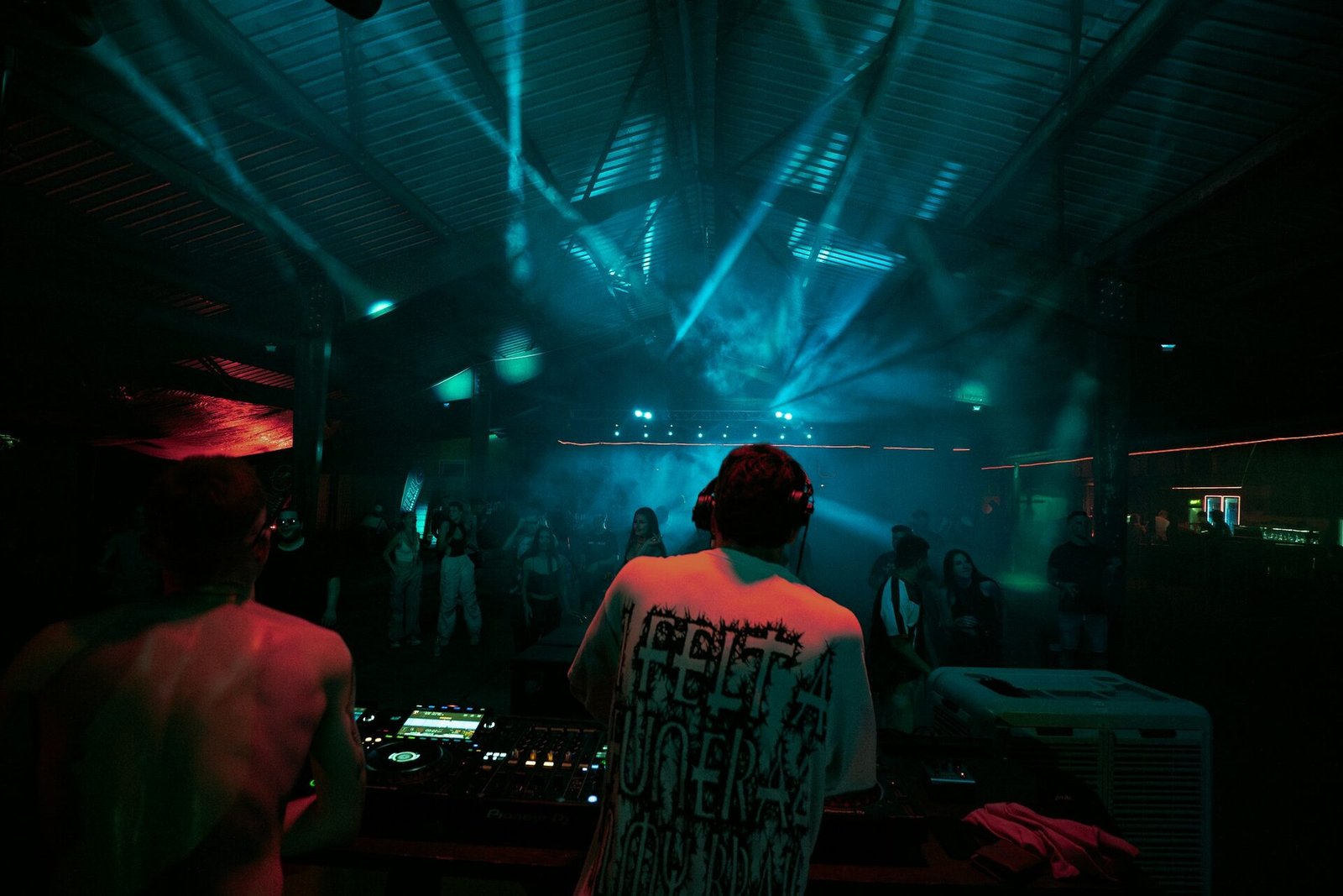 DJ performing behind decks with teal stage lighting